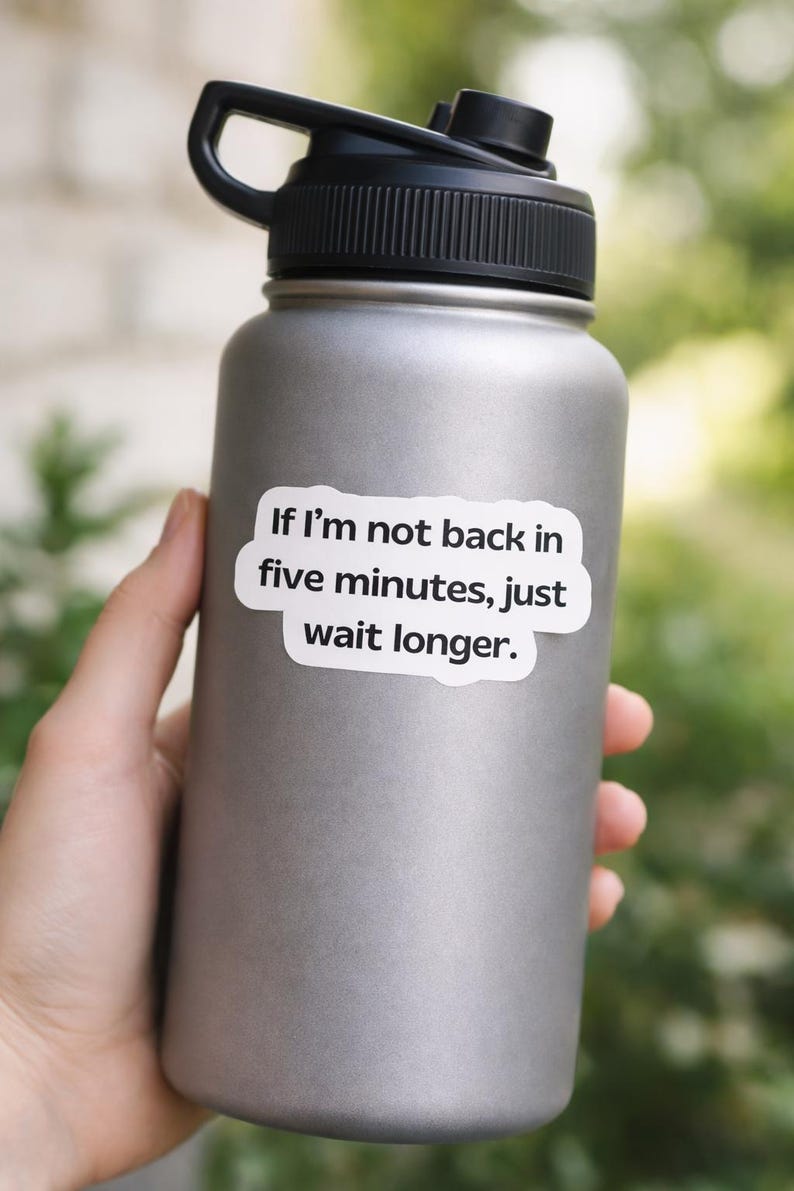 May include: A gray stainless steel water bottle with a black lid and handle. A white sticker on the bottle reads, "If I'm not back in five minutes, just wait longer."