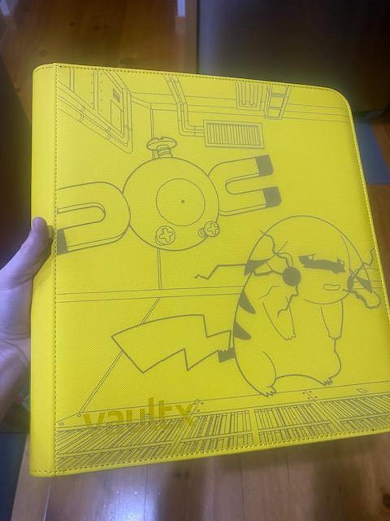 May include: A bright yellow binder featuring a dark grey line art illustration of a Magnemite and a Pikachu character. The cover includes a detailed background design of a room and the word vaultx printed in the bottom left corner of the front.