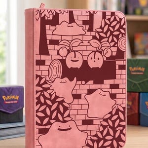 May include: A pink zippered binder featuring a dark red graphic pattern of Ditto and Cherubi characters among trees and brick walls. The cover has a smooth texture and a rectangular shape with rounded corners, designed for storing trading cards.