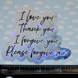 May include: Holographic sticker with the phrases "I love you, Thank you, I forgive you, Please forgive me" in black script. The sticker is cloud-shaped and measures approximately 4 inches in length.