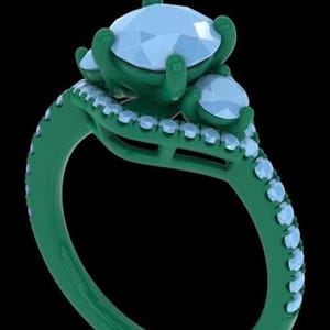 May include: A ring featuring a dark green band and setting with a large, faceted, light blue central stone flanked by two smaller, matching light blue stones. The band is adorned with a row of small, light blue stones along the outer edge.