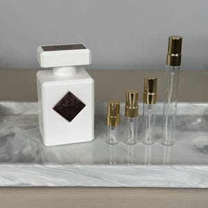 Op de afbeelding: Een set van drie keramische mokken met een gespikkelde, cr&egrave;mekleurige glazuur. Elke mok heeft een ander handgeschilderd ontwerp: een blauw en groen blad, een gele bloem en een rode bes. De mokken hebben een eenvoudige, afgeronde vorm.