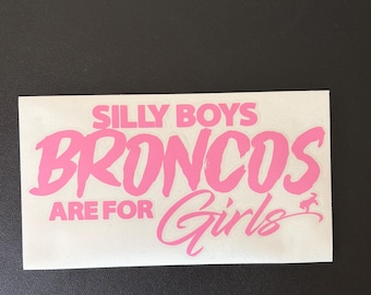 Peut inclure: Autocollant rectangulaire rose vif avec le texte "SILLY BOYS BRONCOS ARE FOR Girls". Le mot "Broncos" est en gras, et "Girls" est en cursive avec un petit graphique de bronco.