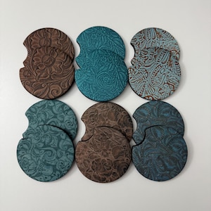 May include: Six car coasters in various colors, including brown, teal, and blue. Each coaster features a unique embossed floral or paisley design. The coasters are round with a curved cutout for easy removal from a car cup holder.