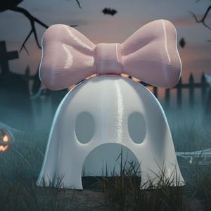 May include: A white ghost figurine featuring a large, smooth, light pink bow on top. The ghost has two oval-shaped eye cutouts and a larger arched opening at the base, creating a hollow structure with a glossy finish and rounded, simple features.
