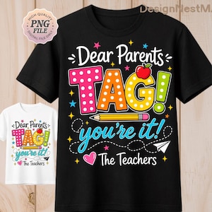 May include: Black t-shirt with the text "Dear Parents TAG! you're it! The Teachers" in colorful letters and graphics. A white t-shirt with the same design is also visible. The design includes an apple, pencil, stars, and a paper airplane.