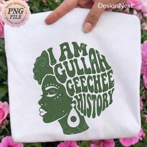 May include: White tote bag with a green graphic of a woman's profile and the text "I AM GULLAH GEECHEE HISTORY". The design has a vintage, textured appearance. The bag is held by a hand.