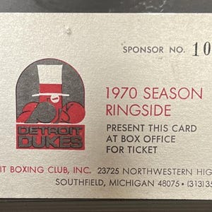 May include: Vintage Detroit Dukes boxing card from 1970, featuring a logo of a boxer in a top hat. The card is silver with red and black text, including "Ringside" and "Sponsor No. 106". The card measures approximately 3.5 x 2 inches.
