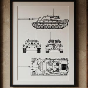 Könnte beinhalten: Schwarz-Weiß-Blaupause eines Panzers, präsentiert in einem schwarzen Rahmen. Der Druck zeigt den Panzer aus verschiedenen Blickwinkeln: Seite, Front, oben. Der Druck hängt an einer beigefarbenen Wand in einem Raum mit Holzakzenten.
