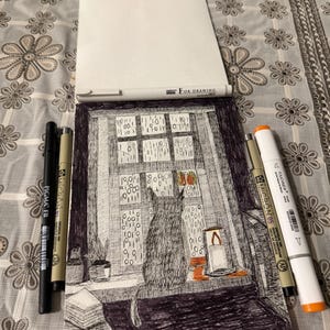 以下が含まれることがあります： 窓の外を眺める猫のペンとインクの絵。窓ガラスにはバイナリコードが描かれています。「FOR DRAWING」と書かれたメモ帳と、様々なペンやマーカーが絵の周りに配置されています。