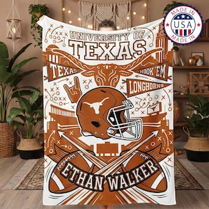 Könnte beinhalten: Weiße und orangefarbene Decke der University of Texas Longhorns. Die Decke zeigt einen Footballhelm, Fußbälle und den Text "ETHAN WALKER". Die Decke hat auch den Text "UNIVERSITY OF TEXAS" und "HOOK 'EM LONGHORNS".