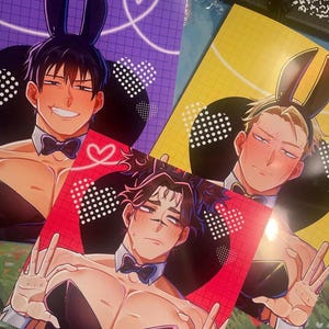 May include: Three colorful prints featuring anime-style characters in bunny ears and bow ties. The prints have backgrounds in purple, yellow, and red, with heart and dot patterns. The characters are smiling and making peace signs.