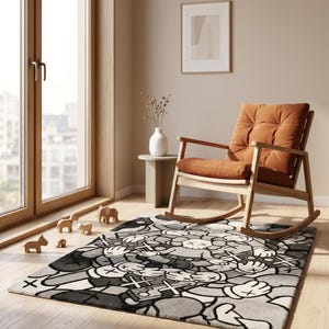 May include: A rectangular area rug featuring a repeating pattern of cartoon-style characters with gloved hands and X-shaped eyes in shades of gray, black, and white. The rug is positioned on a light wood floor in a room with a wooden rocking chair.