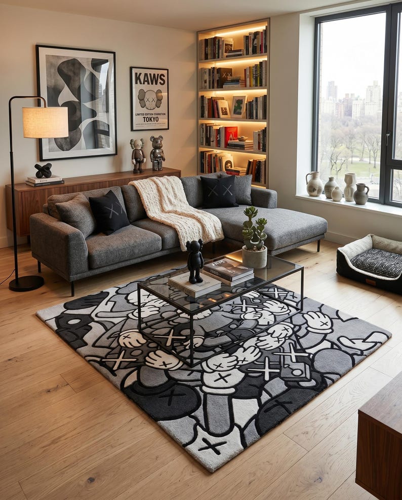 May include: A rectangular area rug featuring a repeating grayscale graphic pattern of cartoon-style gloved hands and cross-shaped eyes. The rug is positioned under a rectangular glass-top coffee table with a black metal frame in a living room.