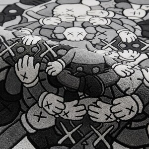 May include: A textured rug featuring a repeating pattern of cartoon-style figures with X-shaped eyes and gloved hands covering their faces. The design is rendered in shades of black, gray, and white, with a folded corner revealing the pile texture.