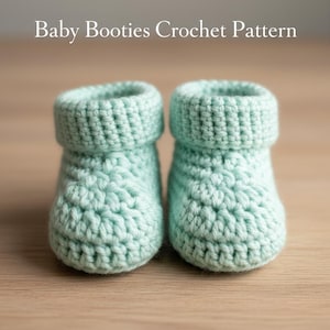 May include: Two light teal crochet baby booties with folded-over cuffs. The booties are made with a textured stitch pattern and sit on a light brown surface. The text "Baby Booties Crochet Pattern" is at the top.