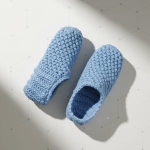 May include: A pair of light blue crocheted slippers. The slippers are made of a textured yarn and have a closed toe and heel. The slippers are designed to be worn indoors.