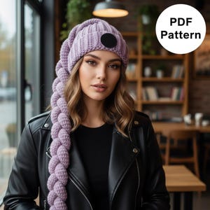 May include: A lavender knit hat with a long, braided extension. The hat features a ribbed design and a black circular patch. The image also includes the text "PDF Pattern" in a white circle. The person in the image is wearing a black leather jacket.
