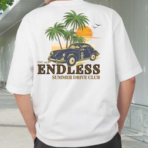 May include: White t-shirt featuring a graphic of a vintage blue car, palm trees, and a sunset. The text "ENDLESS SUMMER DRIVE CLUB" is printed below the graphic, with "EST. 1978" above. The shirt has short sleeves.
