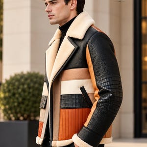 Puede incluir: Una chaqueta de cuero con bloques de color en tonos negro, tostado y naranja con acabado texturizado. La prenda incluye cuello y pu&ntilde;os de borrego color crema, cierre de cremallera frontal y el texto MontreuxLeather en la esquina superior.
