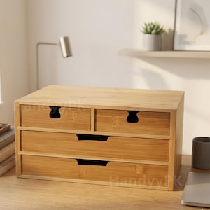 May include: A bamboo desk organizer with four drawers. The organizer has a natural wood finish and a rectangular shape. The drawers have curved cutouts for handles. The organizer is sitting on a wooden desk.