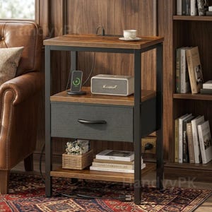 May include: A brown and black nightstand with a drawer and two shelves. The nightstand has a charging station, a speaker, and a small basket. A cup and books are also visible. The nightstand is approximately 24 inches tall.