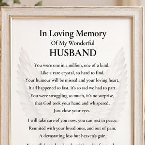 May include: A rectangular light-coloured wooden frame containing a white print with the text In Loving Memory Of My Wonderful HUSBAND followed by a poem. The background of the text features a faint, light grey illustration of two angel wings.