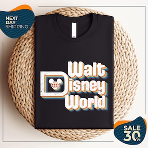 A black t-shirt with the text "Walt Disney World" printed on it, along with a Mickey Mouse logo. The t-shirt is displayed on a woven placemat, and there are two sale signs indicating a 30% discount on the item.