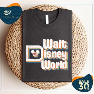 A black t-shirt with the text "Walt Disney World" printed on it, along with a Mickey Mouse logo. The t-shirt is displayed on a woven basket, and there are two sale signs indicating a 30% discount.