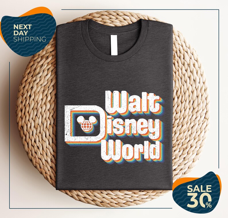 A black t-shirt with the text "Walt Disney World" printed on it, along with a Mickey Mouse logo. The t-shirt is displayed on a woven basket, and there are two sale signs indicating a 30% discount.