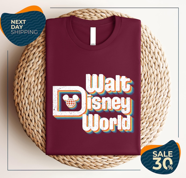 A burgundy t-shirt with the text "Walt Disney World" printed on it, displayed on a woven basket.