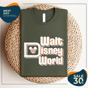 A green t-shirt with the text "Walt Disney World" printed on it, placed on a woven basket.