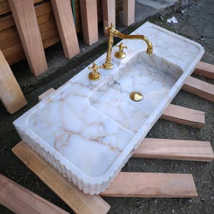 Handmade in Turkey, our marble kitchen sinks and utility sinks are carved from rich stones like ata marble and aegean marble. Whether you need a workstation sink or a charming farmhouse sink, our marble adds a luxurious touch. Transform your space with a marble wall sink or marble countertop sink. Featuring calacatta marble, travertine, and italian marble sinks. Luxury marble sinks made from aegean marble, carrara, and calcutta marble. Wall-mounted, pedestal, and floating styles available.