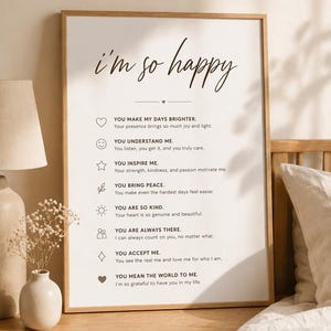 May include: A framed print with the words "i'm so happy" in elegant script. The print includes a list of sentiments such as "You make my days brighter" and "You understand me", with corresponding icons.