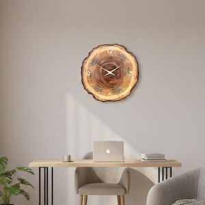 May include: A round wooden clock with a natural wood grain finish hangs on a light-colored wall. The clock features a light brown face with black numerals and gold-colored hands. The clock is a decorative element in a modern office setting.