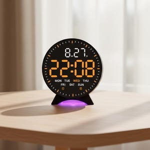 Op de afbeelding: Een zwarte digitale wekker met de tijd 22:08 en de datum 8.27. De klok heeft een cirkelvormig ontwerp met oranje cijfers en een kleine standaard. De dagen van de week worden onderaan weergegeven. De klok staat op een houten tafel.