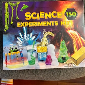 May include: A colorful science experiments kit box with the text "SCIENCE EXPERIMENTS KIT 150". The box features illustrations of various science experiments, including a volcano, crystals, and beakers with colorful liquids.