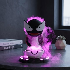 Könnte beinhalten: Eine schwarz-weiß-Themenlampe mit einem lila Dampfeffekt. Die Lampe hat einen runden Kopf mit weißen Augen und einem roten Mund. Der Sockel ist weiß und schwarz mit einem leuchtenden lila Licht.