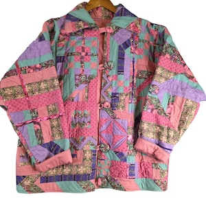 May include: A patchwork jacket in a variety of colors, including pink, lavender, and teal. The jacket features a quilted design with floral and geometric patterns. It has a collared neckline, long sleeves, and button closures.