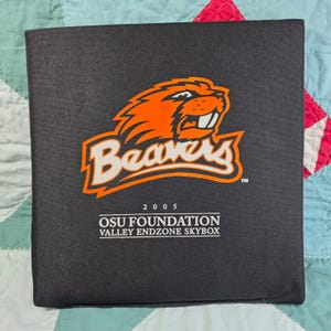 May include: A black square binder featuring an orange and white beaver mascot logo above the text 2005 OSU FOUNDATION VALLEY ENDZONE SKYBOX. The cover has a textured fabric finish and displays the team name Beavers in a stylized white font.