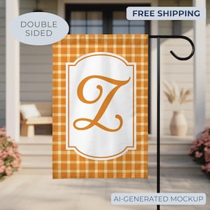 May include: A rectangular garden flag featuring an orange and white plaid pattern. In the center, a white rectangular frame with rounded corners contains a large, orange, cursive letter Z. The flag hangs from a black metal stand.
