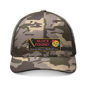 May include: Camouflage trucker cap with a mesh back and a curved peak. The front panel has a patch with the words "BLOCK FOUND", a mining pickaxe graphic, and an emoji. The text below reads "Chance per block 1 in 788,991,047 chance."