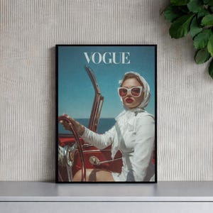 Peut inclure: Une œuvre d'art encadrée représentant une couverture du magazine Vogue. On y voit une femme portant un foulard blanc et des lunettes de soleil conduisant un cabriolet rouge. Le logo Vogue est en haut.