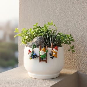 May include: A white ceramic mug with a black handle and the text "But first, coffee" in a black, handwritten-style font. The mug is on a white surface.