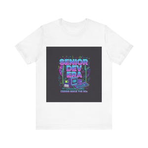 May include: White t-shirt with a retro graphic. The design features the words "SENIOR DEV ERA" in a blue and pink gradient, and an illustration of a computer and keyboard. The text "CODING SINCE THE 80s" is also included in the design.
