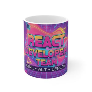 May include: White ceramic mug with a colourful design. The mug features the words "REACT DEVELOPER TEAM" in a retro font, with "CTRL + ALT + DEPLOY" below. The background has a grid pattern with pink, purple, and orange colours.
