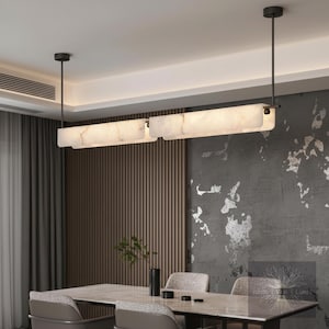 May include: Two rectangular pendant lights with a marble effect hang above a dining table. The lights are suspended from the ceiling by thin black rods. The room has a neutral colour palette with grey walls and a wooden accent wall.