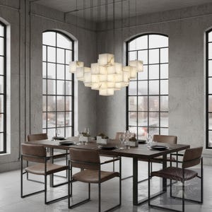 May include: A modern dining room featuring a dark wood table with six chairs. Above the table hangs a unique chandelier composed of illuminated, square, white blocks. Large windows provide a view of the city.