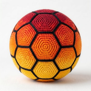Peut inclure: Un ballon de football crocheté à la main, aux couleurs dégradées, passant du rouge au jaune. Les panneaux du ballon sont soulignés de noir, créant un motif géométrique distinct. Un article unique et fait à la main.