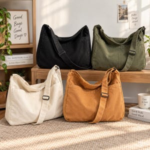 May include: Four canvas crossbody bags in black, olive green, off-white, and tan. Each bag features a wide adjustable shoulder strap, a spacious main compartment, and an exterior slip pocket on the front, showcasing a simple, functional design.